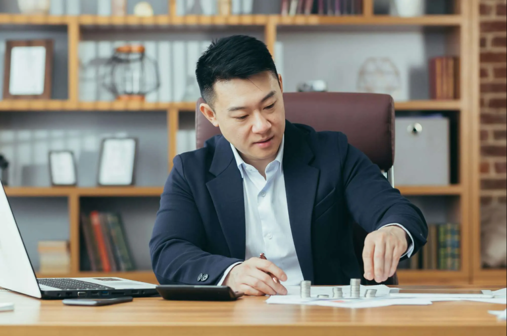 Aml For Gold And Precious Metals Dealers In Dubai, Uae 2 an asian banker works in a classic office at a table counting coins made of precious metals